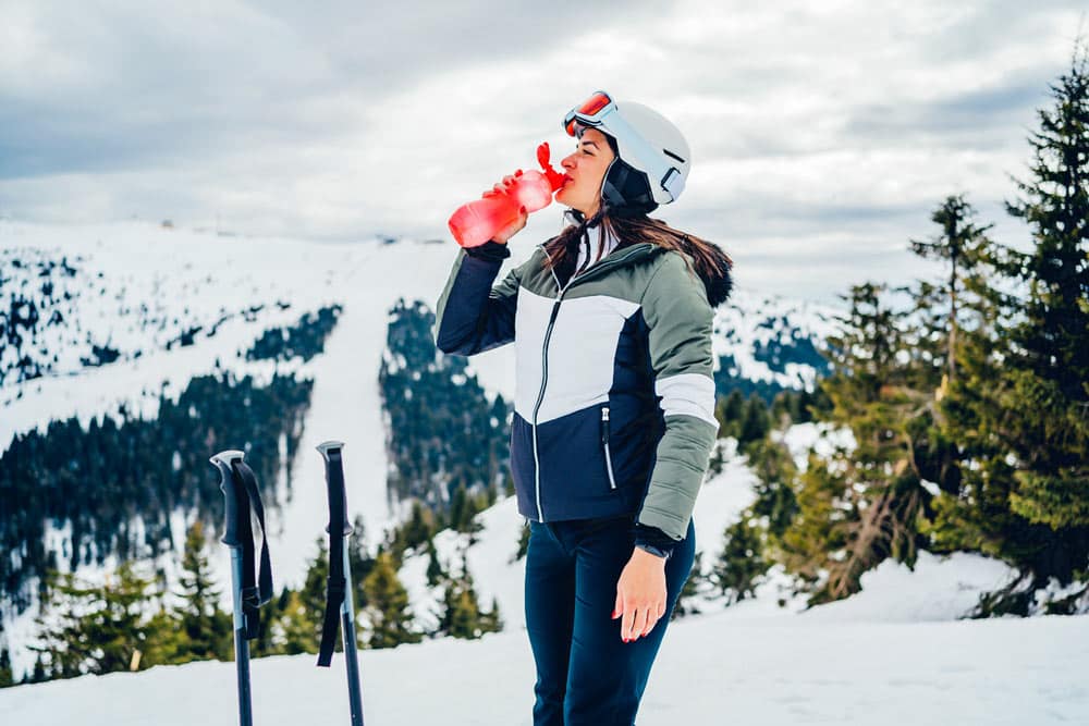 Woman drinking water in preparation for winter sports.