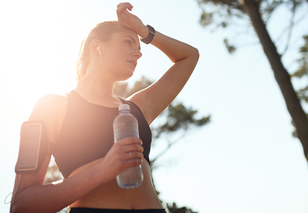 Shot of a fit woman stopping for a drink of water during a run outdoors.
