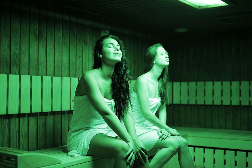 Two women relaxing inside a sauna.
