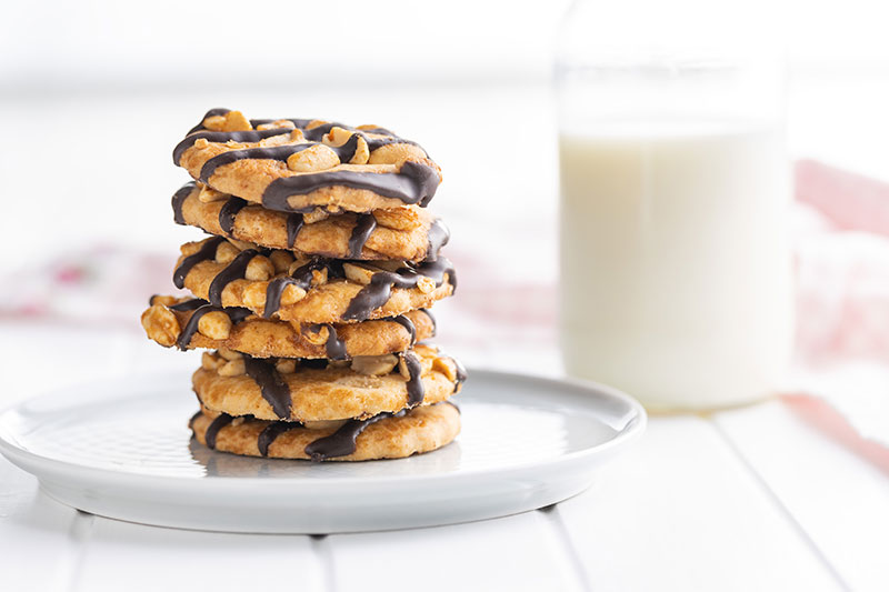 A plate with a stack of cookies and a side glass of milk.