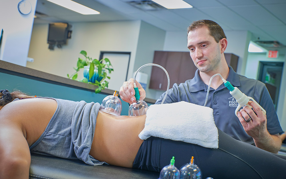Physical therapist cupping the patients' back.