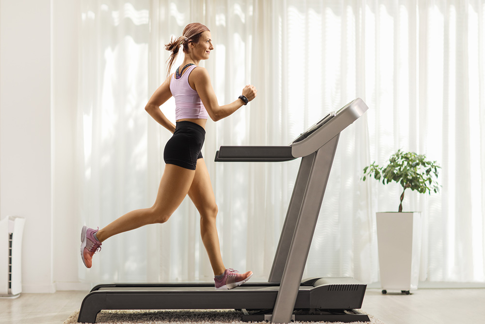 Woman using home treadmill to exercise.