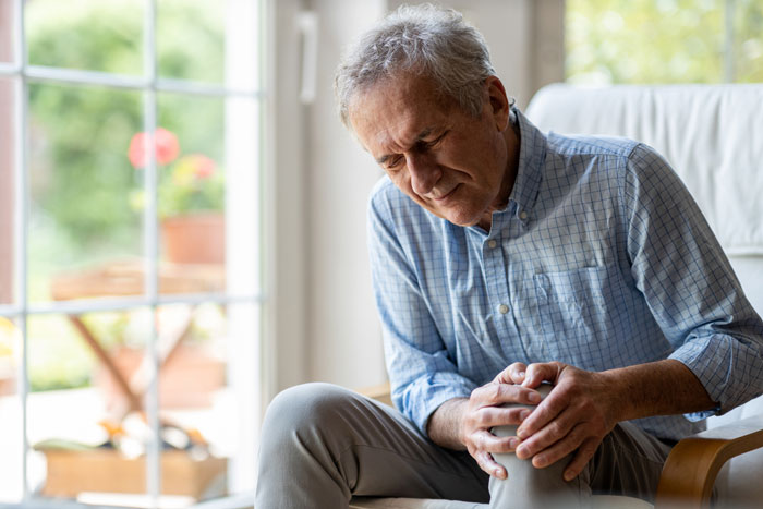 Senior man holds knee in pain