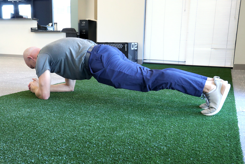 Physical therapist demonstrating plank to improve golf game.