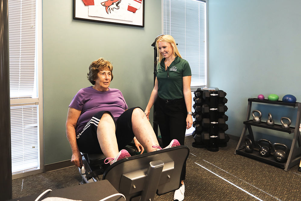 Physical therapist helping patient with leg pushes.