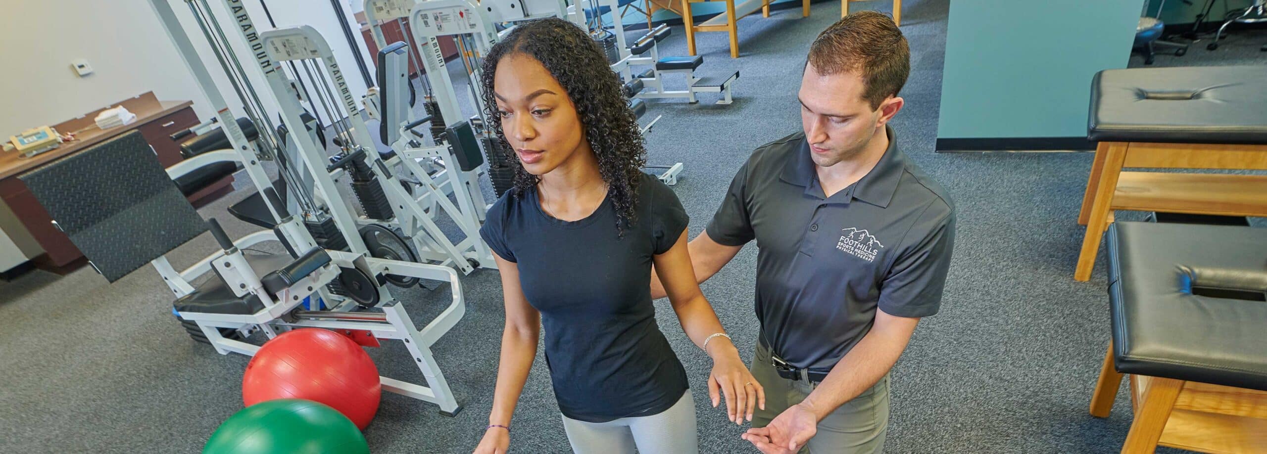 Female patient with male PT adjusting her back while standing