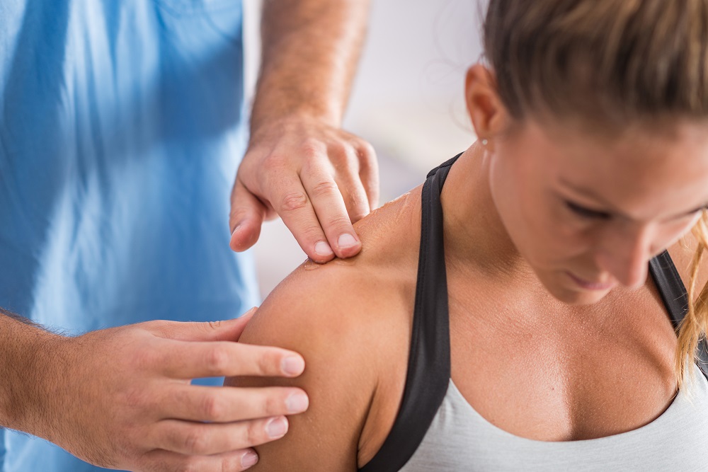 Physical therapist treating a woman's shoulder.