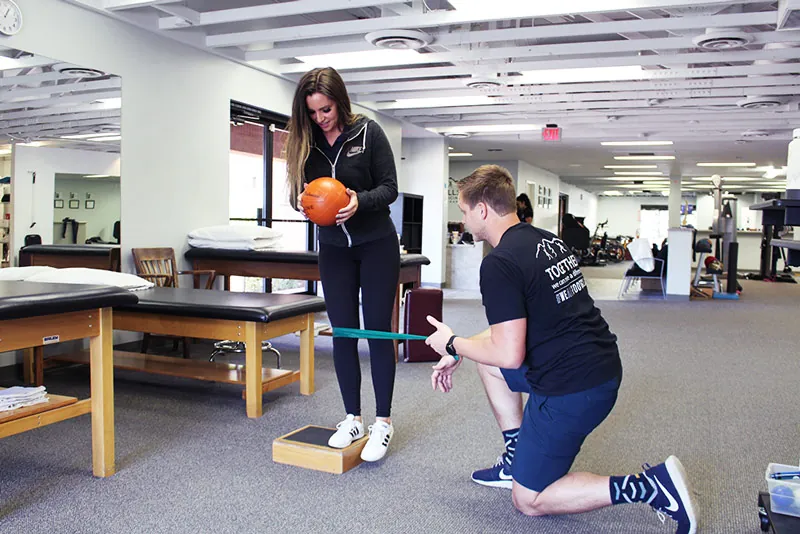 Physical therapist working with patient's leg.