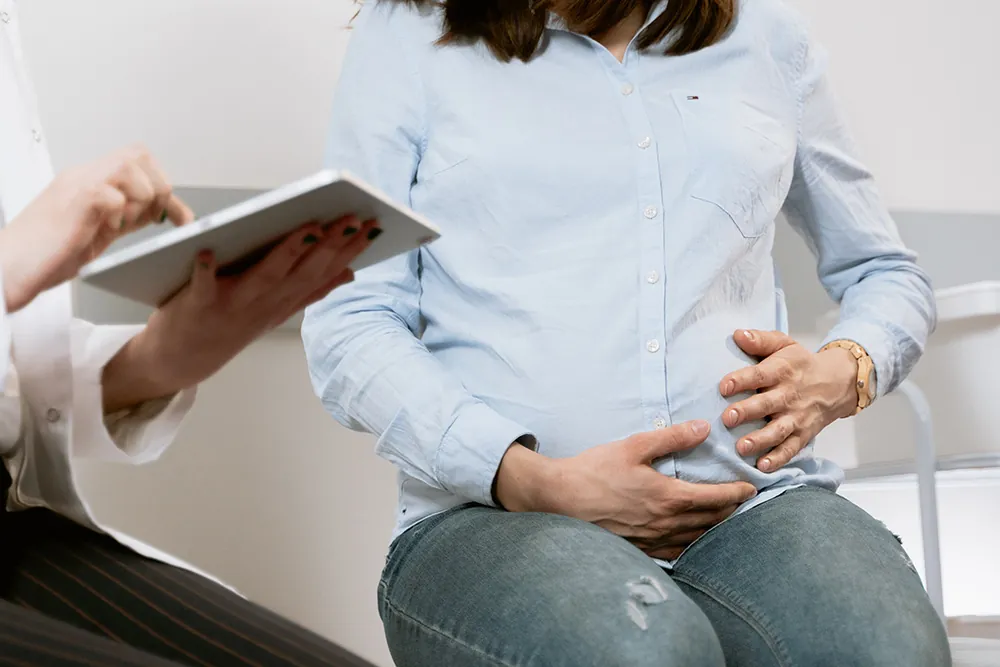 Pregnant woman touching belly.