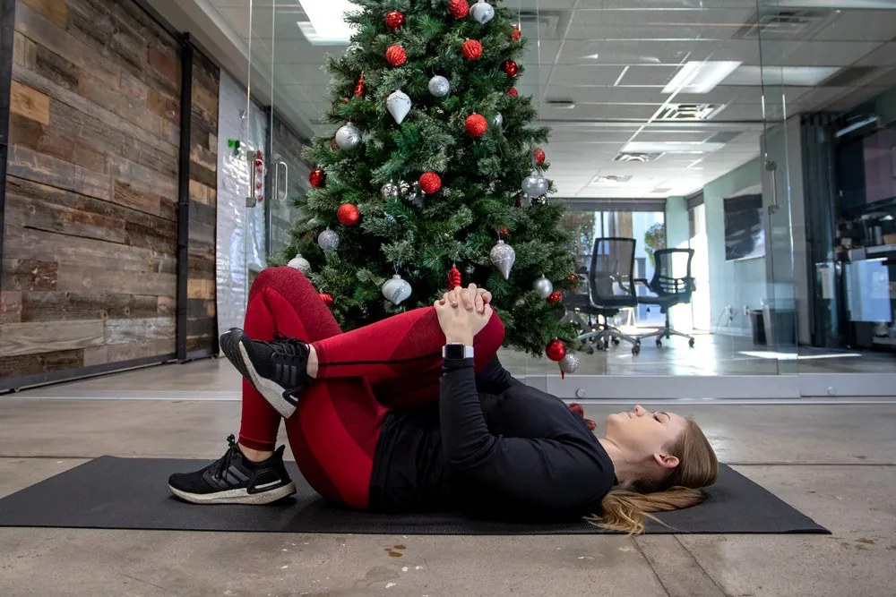 Woman stretching leg in front of Christmas tree