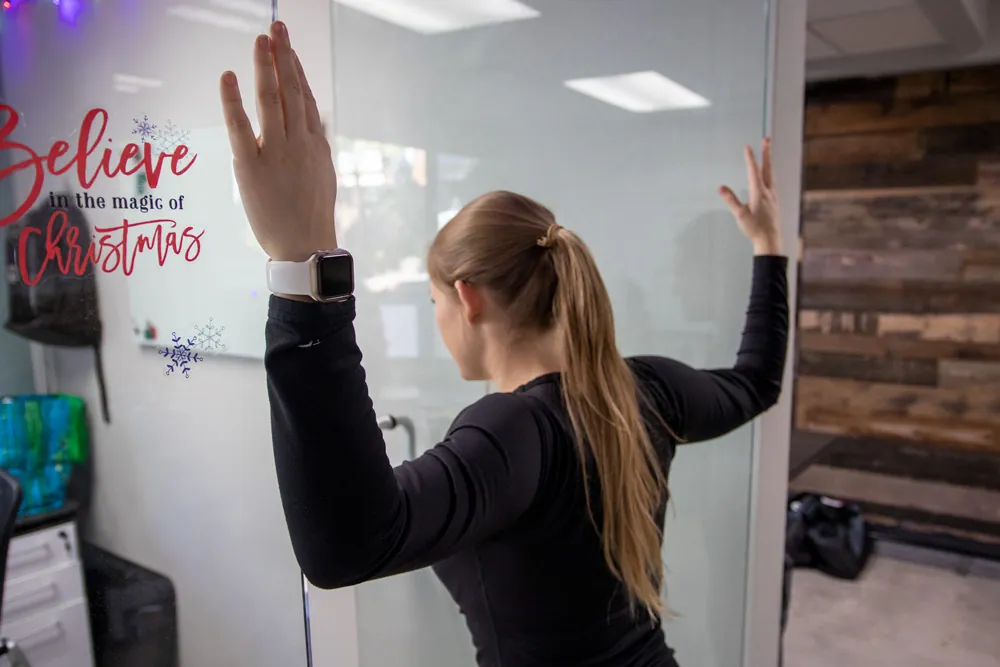 Woman stretching shoulders in doorway