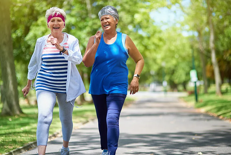 Two women walking outside with smiles on their face.