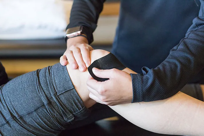 Therapist using kineosio tape on patients leg.