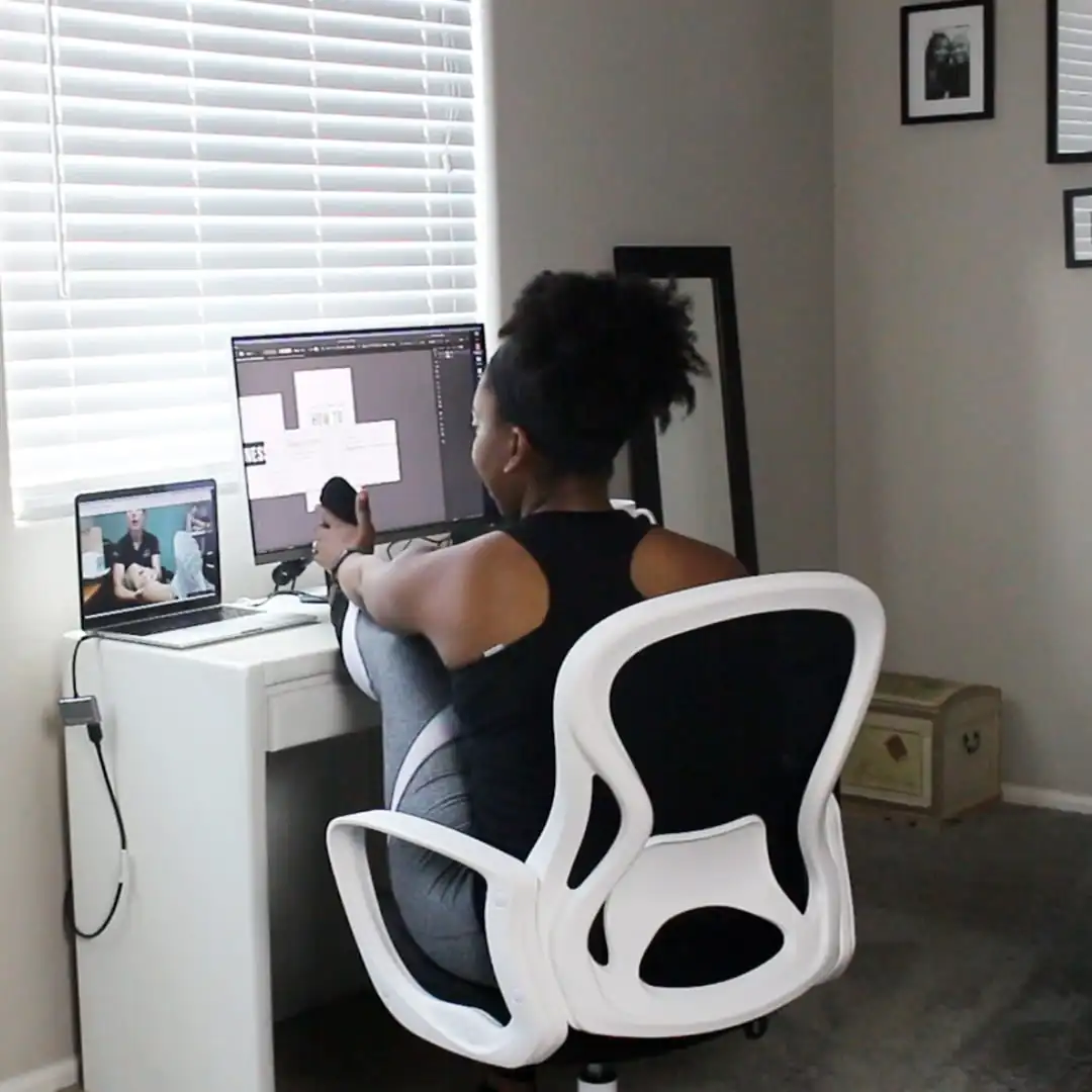 woman sitting at her desk on a telehealth physical therapy appointment holding her foot