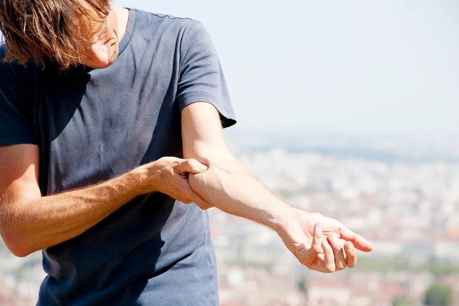 Man holding elbow in pain while playing tennis 