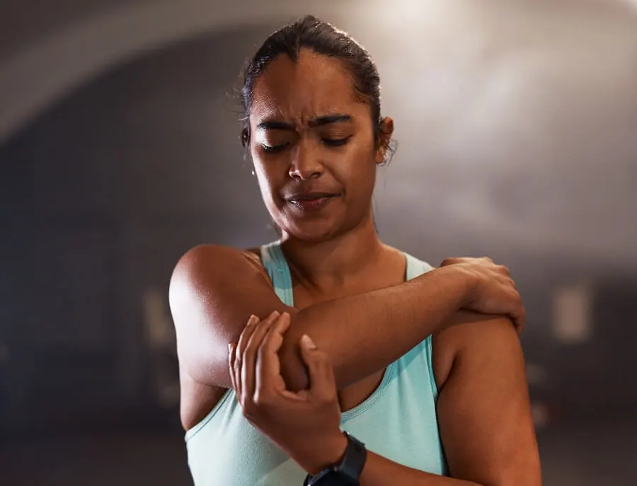Young woman experiencing pain while working out in a gym.