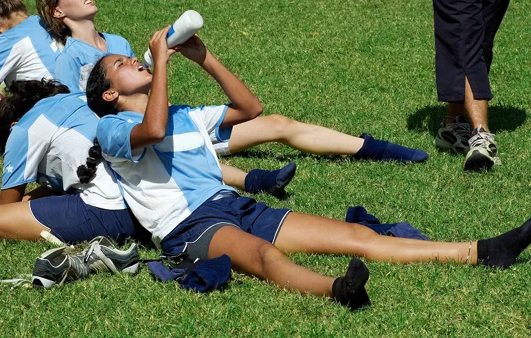 Soccer kids drinking water on the field.
