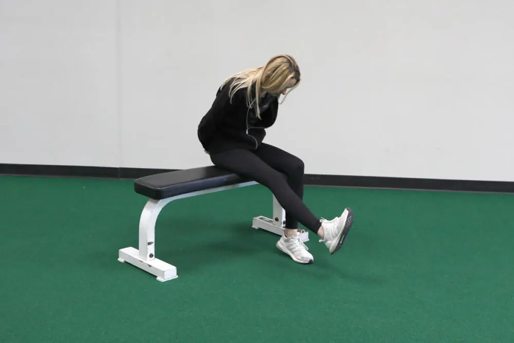 Female athlete on a bench stretching toes.