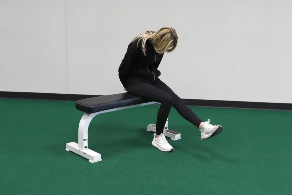 Female athlete on a bench stretching toes.