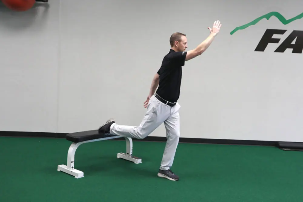 Athletic trainer stretching on gym floor.
