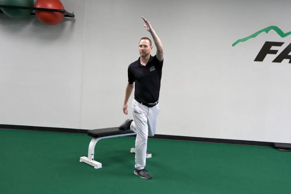 Athletic trainer stretching on gym floor.