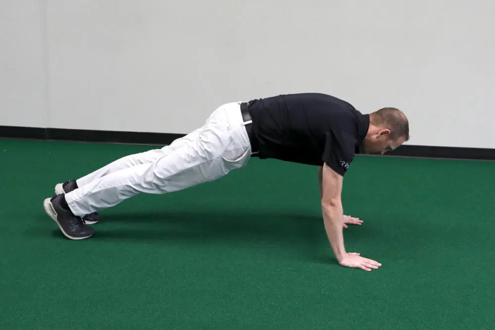 Athletic trainer stretching on gym floor.