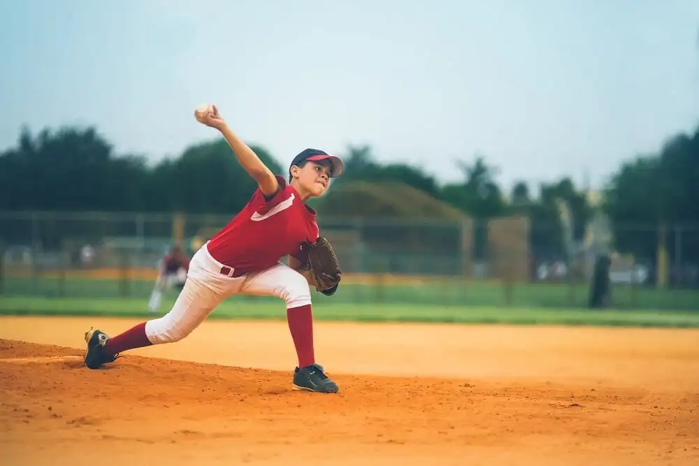 Baseball pitcher throwing the ball off of the pitchers mound.