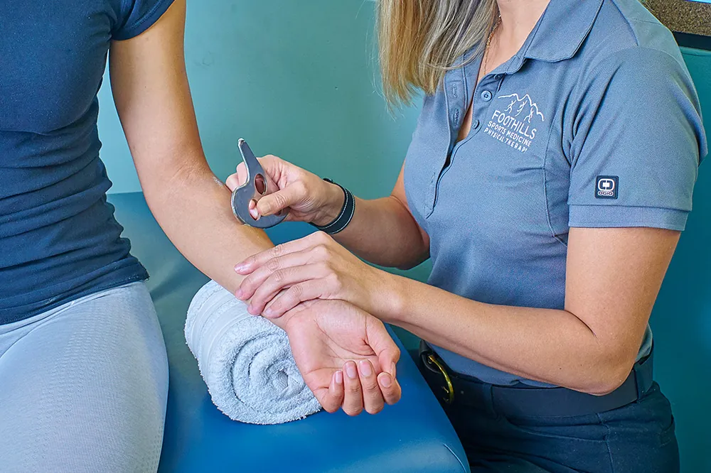 Physical therapist performing IASTM to promote healthy tissue healing on patients arm.