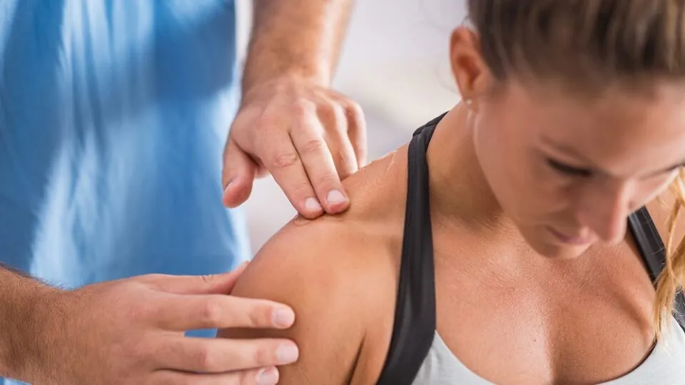 Physical therapist treating a woman's shoulder.